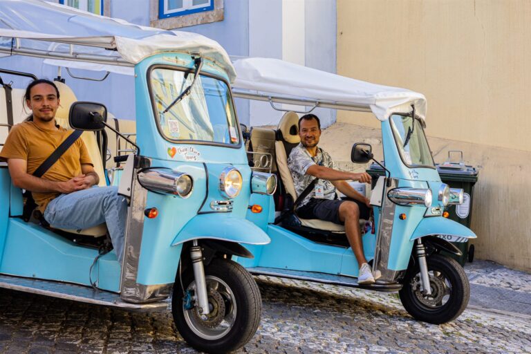 Guests sitting in the back of a light blue electric tuk-tuk in central Lisbon