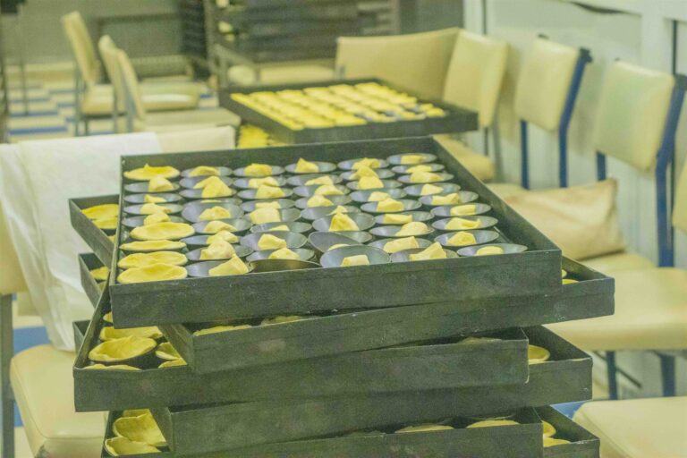 Trays of custard tarts being prepared in the Pasteis de Belem kitchen