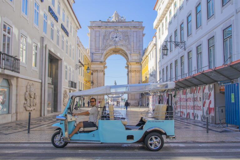 The Rua Augusta Arch in Lisbon Baixa district with a tuk-tuk passing