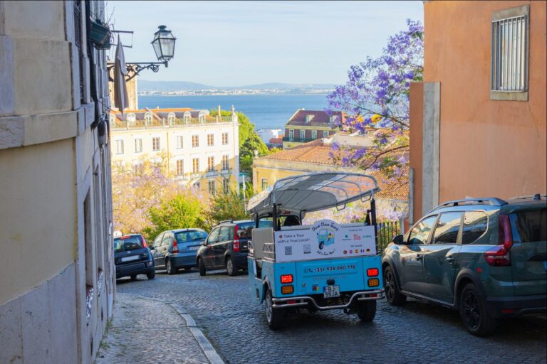 A tuk-tuk on a Lisbon hillside street with the Tagus river beyond