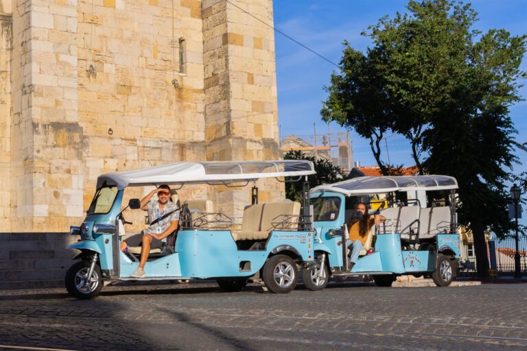 Two Chico Chico Tours tuk-tuks with guests parked beside Lisbon Cathedral